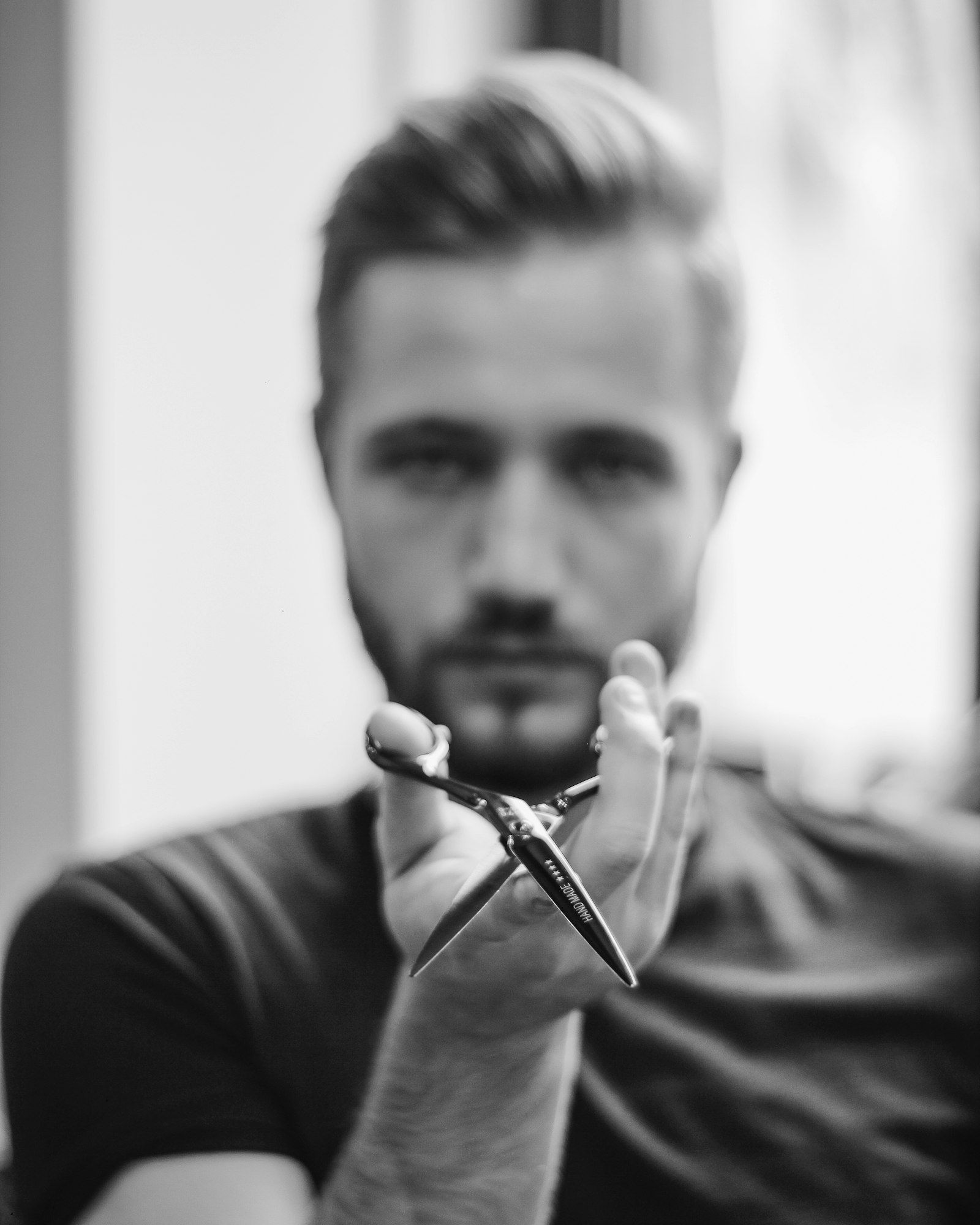 Barber drží nůžky a dívá se do objektivu